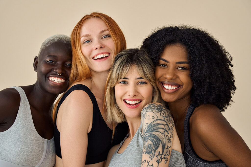 A group of women of varying skin tones smile, at ease knowing they can work with our providers to plan personalized laser hair removal for dark skin near Kitchener.